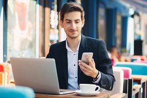 Ein junger Mann nutzt seinen Laptop und sein Smartphone, um Sack zu kontaktieren.